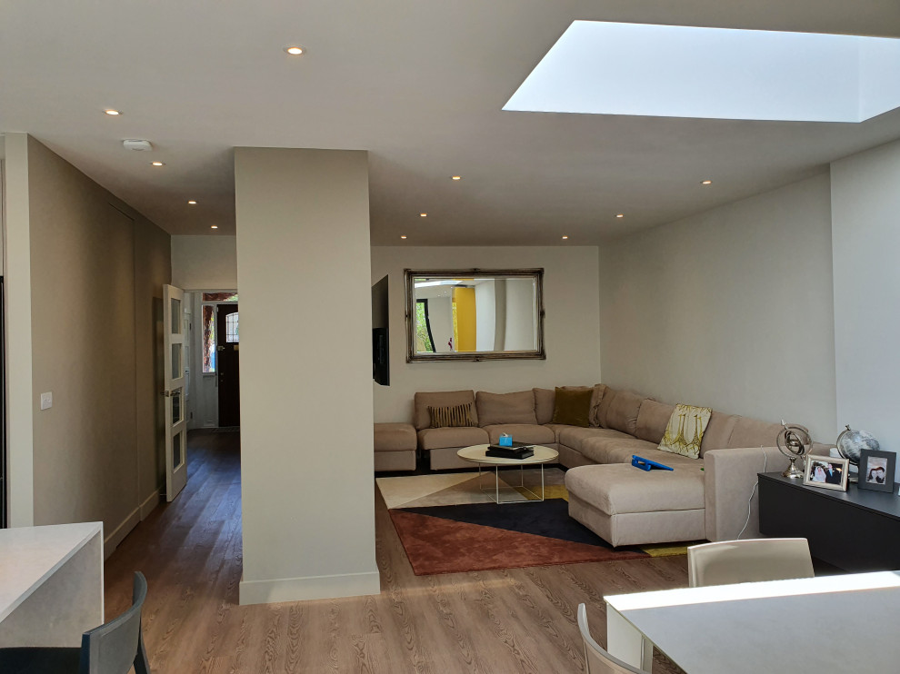 На фото: открытая гостиная комната среднего размера в современном стиле с белыми стенами, полом из линолеума и коричневым полом с
