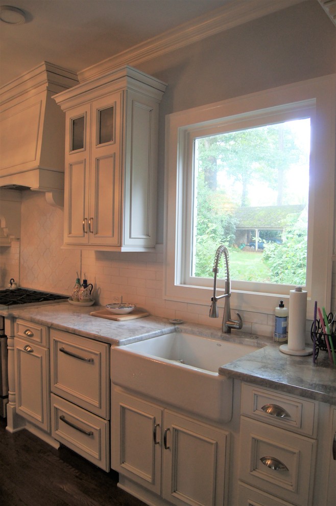 Example of a large transitional single-wall dark wood floor and brown floor kitchen design with a farmhouse sink, marble countertops, white backsplash, stainless steel appliances and an island
