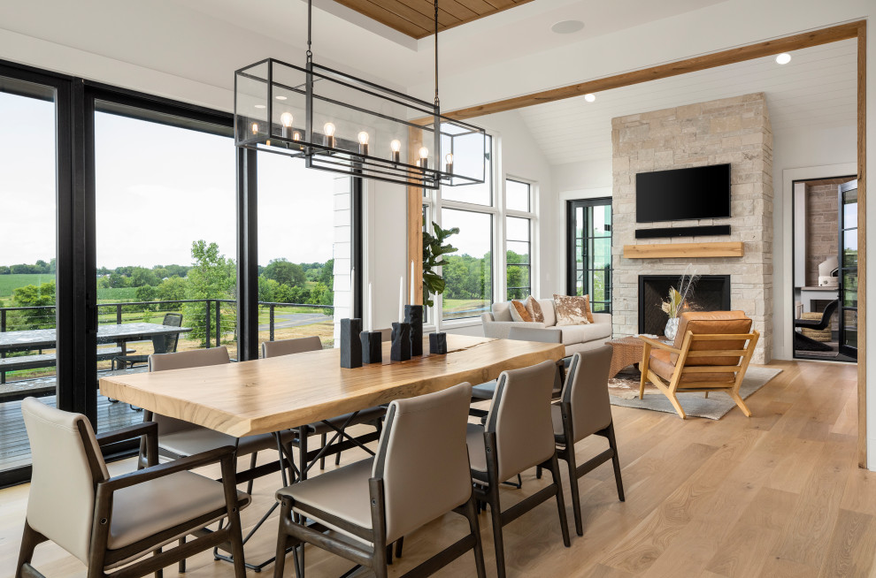 This is an example of a transitional open plan dining in Minneapolis with white walls, medium hardwood floors, a standard fireplace, a stone fireplace surround, brown floor and wood.