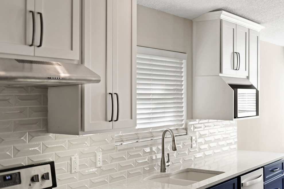 Large transitional l-shaped vinyl floor and brown floor open concept kitchen photo in Jacksonville with an undermount sink, shaker cabinets, blue cabinets, quartzite countertops, white backsplash, ceramic backsplash, stainless steel appliances and a peninsula