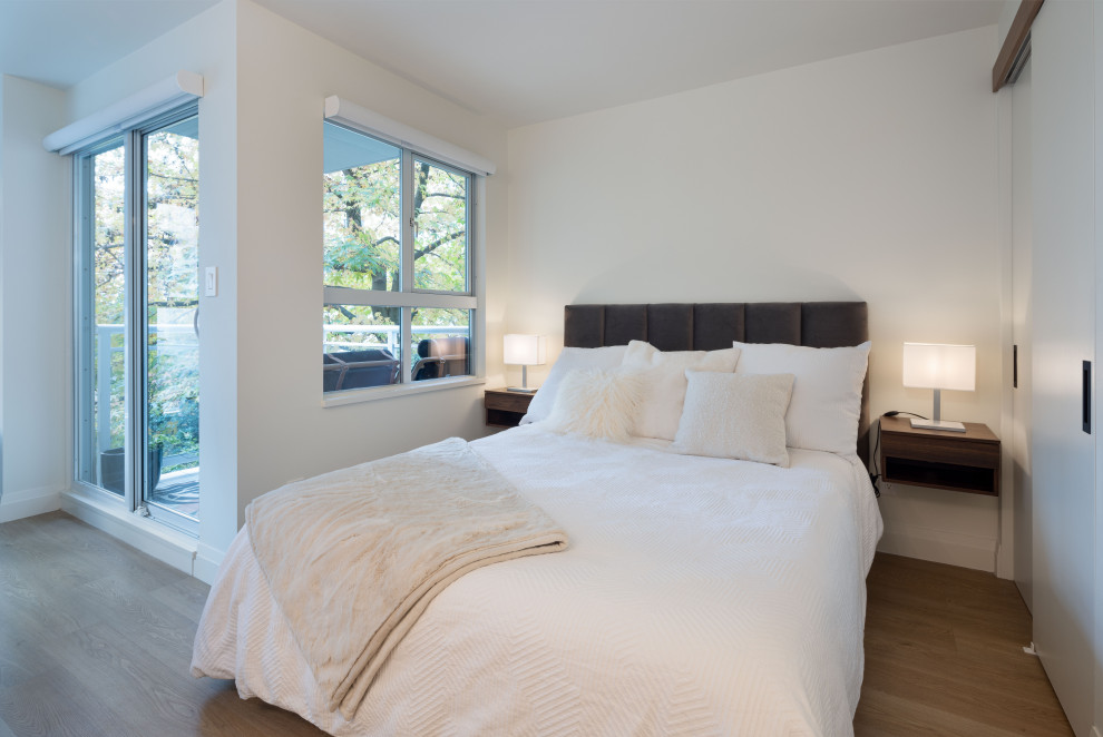 На фото: маленькая гостевая спальня (комната для гостей) в современном стиле с белыми стенами, полом из ламината и коричневым полом для на участке и в саду