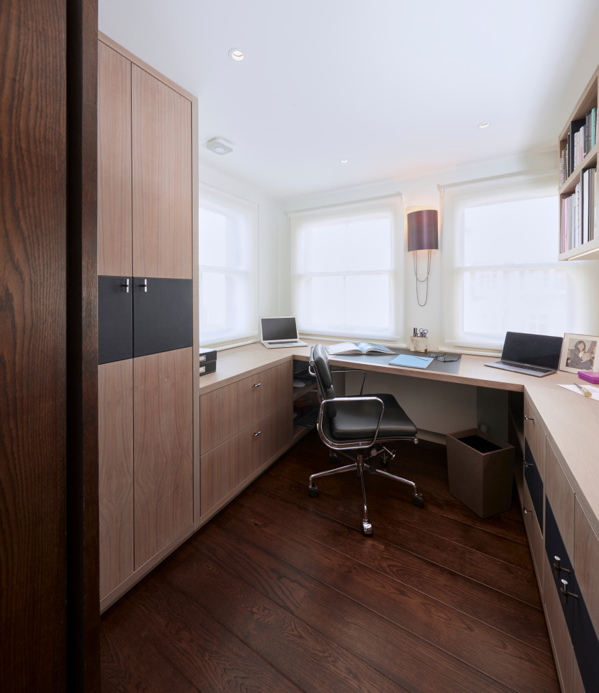 Cette photo montre un petit bureau tendance avec un mur blanc, parquet foncé, un bureau intégré et un sol marron.