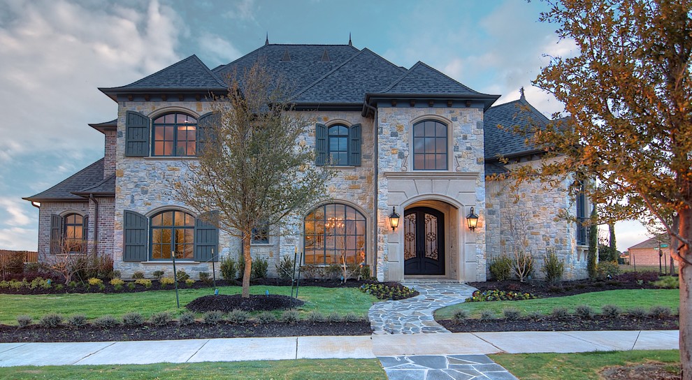 Inspiration for a large traditional two-storey exterior in Dallas with stone veneer.