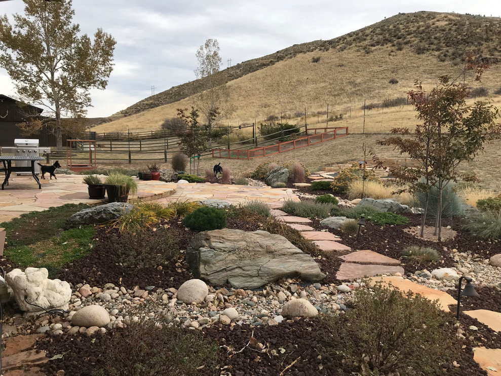 Photo of a large country backyard full sun xeriscape in Denver with a fire feature and natural stone pavers.