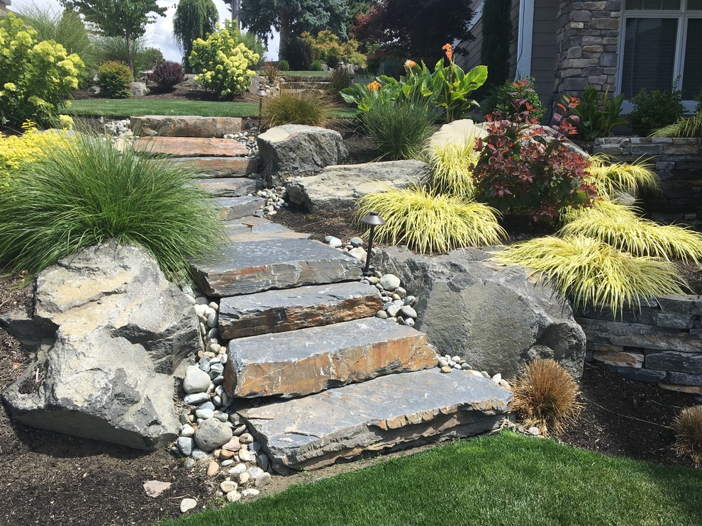 Mid-sized transitional sloped full sun xeriscape in Seattle with a retaining wall and natural stone pavers.