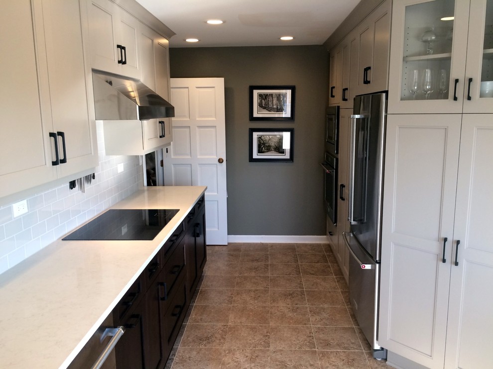 Enclosed kitchen - small transitional galley porcelain tile enclosed kitchen idea with a farmhouse sink, recessed-panel cabinets, white cabinets, quartz countertops, white backsplash, subway tile backsplash and stainless steel appliances