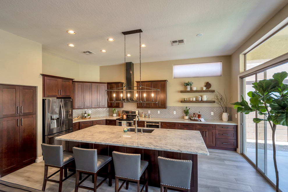 Example of a mid-sized transitional l-shaped porcelain tile and brown floor open concept kitchen design in Phoenix with a single-bowl sink, shaker cabinets, brown cabinets, granite countertops, gray backsplash, brick backsplash, stainless steel appliances, an island and multicolored countertops