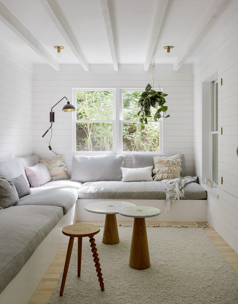 This is an example of a scandinavian enclosed living room in New York with white walls and light hardwood floors.