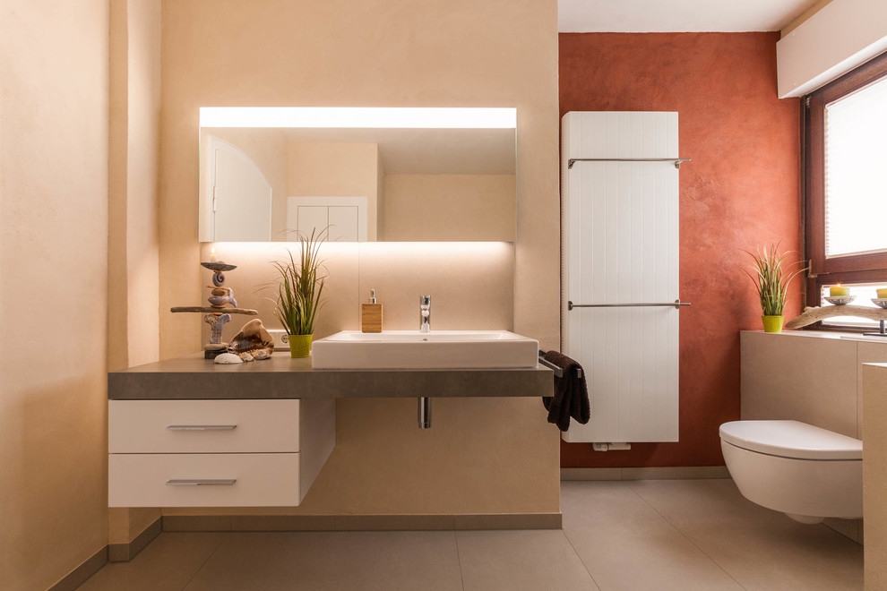 Design ideas for a mid-sized contemporary 3/4 bathroom in Other with flat-panel cabinets, white cabinets, a wall-mount toilet, beige walls, cement tiles, a vessel sink and beige floor.