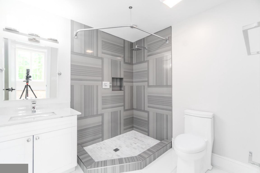 Trendy 3/4 gray tile white floor and single-sink bathroom photo in DC Metro with flat-panel cabinets, white cabinets, a one-piece toilet, white walls, an undermount sink, white countertops, a niche and a floating vanity