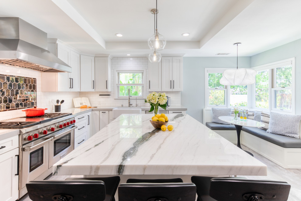 Photo of a mid-sized modern separate kitchen in San Francisco with a farmhouse sink, shaker cabinets, white cabinets, marble benchtops, white splashback, ceramic splashback, stainless steel appliances, with island, grey floor, white benchtop and coffered.