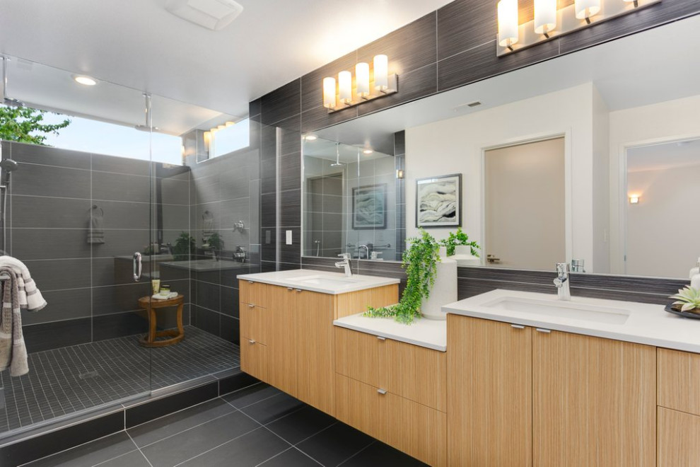 This is an example of a large contemporary master bathroom in Seattle with flat-panel cabinets, light wood cabinets, gray tile, ceramic tile, grey walls, ceramic floors, grey floor, white benchtops, an alcove shower, an undermount sink, a hinged shower door, a double vanity and a floating vanity.