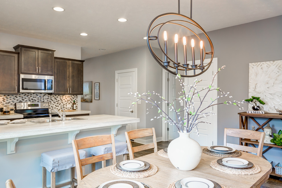 Mid-sized transitional galley vinyl floor eat-in kitchen photo with a double-bowl sink, recessed-panel cabinets, dark wood cabinets, laminate countertops, multicolored backsplash, ceramic backsplash, stainless steel appliances and an island