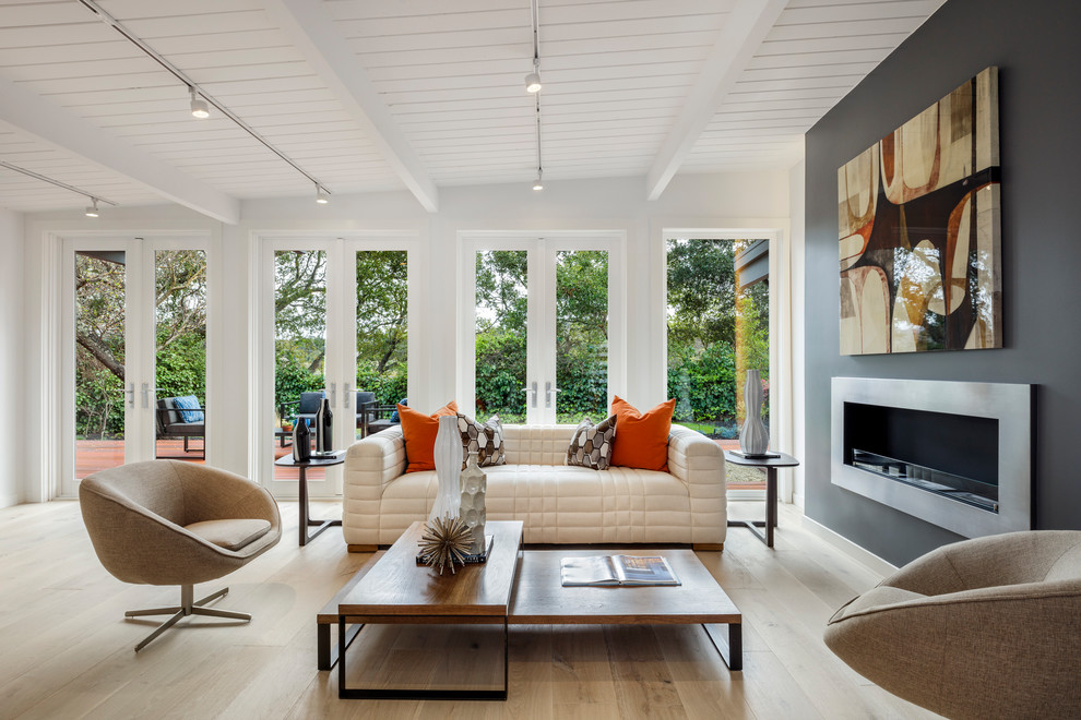 Contemporary family room in San Francisco with white walls, light hardwood floors, a ribbon fireplace, a metal fireplace surround and beige floor.