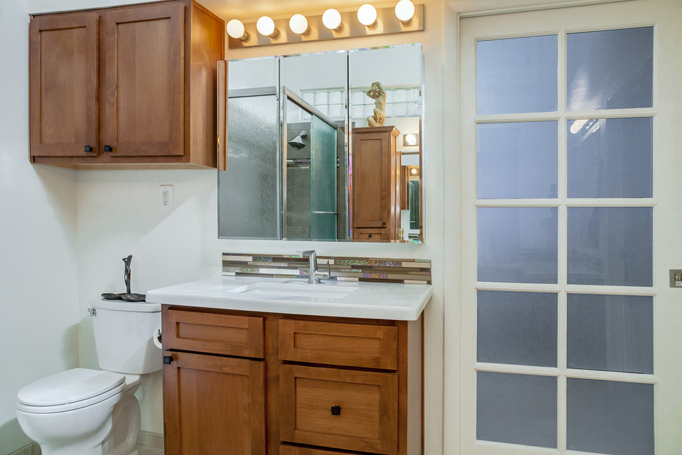 Example of a large transitional master brown tile and porcelain tile porcelain tile and beige floor corner bathtub design in Phoenix with recessed-panel cabinets, medium tone wood cabinets, a one-piece toilet, beige walls, an undermount sink and quartz countertops
