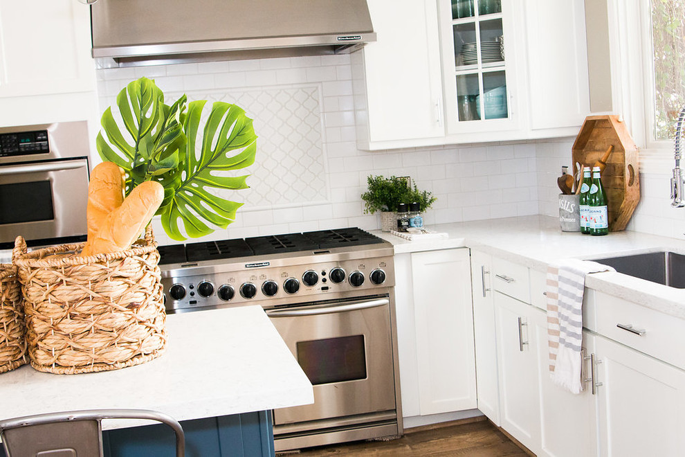 Example of a small transitional single-wall laminate floor and brown floor open concept kitchen design in Phoenix with an undermount sink, shaker cabinets, white cabinets, quartz countertops, white backsplash, subway tile backsplash, stainless steel appliances and an island
