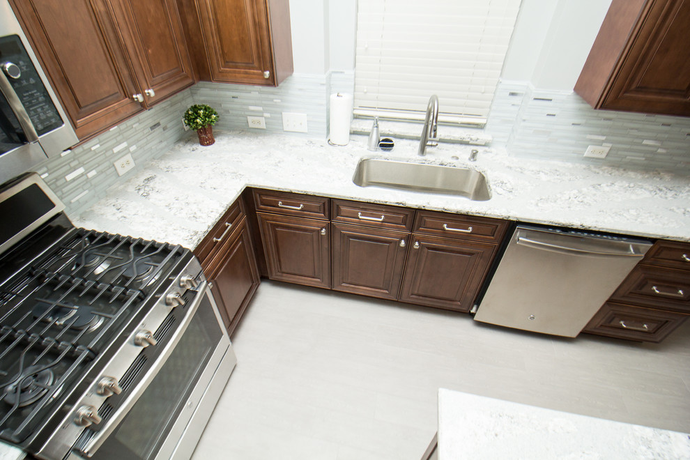 Inspiration for a mid-sized transitional l-shaped porcelain tile and gray floor open concept kitchen remodel in Houston with a single-bowl sink, raised-panel cabinets, medium tone wood cabinets, quartz countertops, mosaic tile backsplash, stainless steel appliances, two islands and white backsplash
