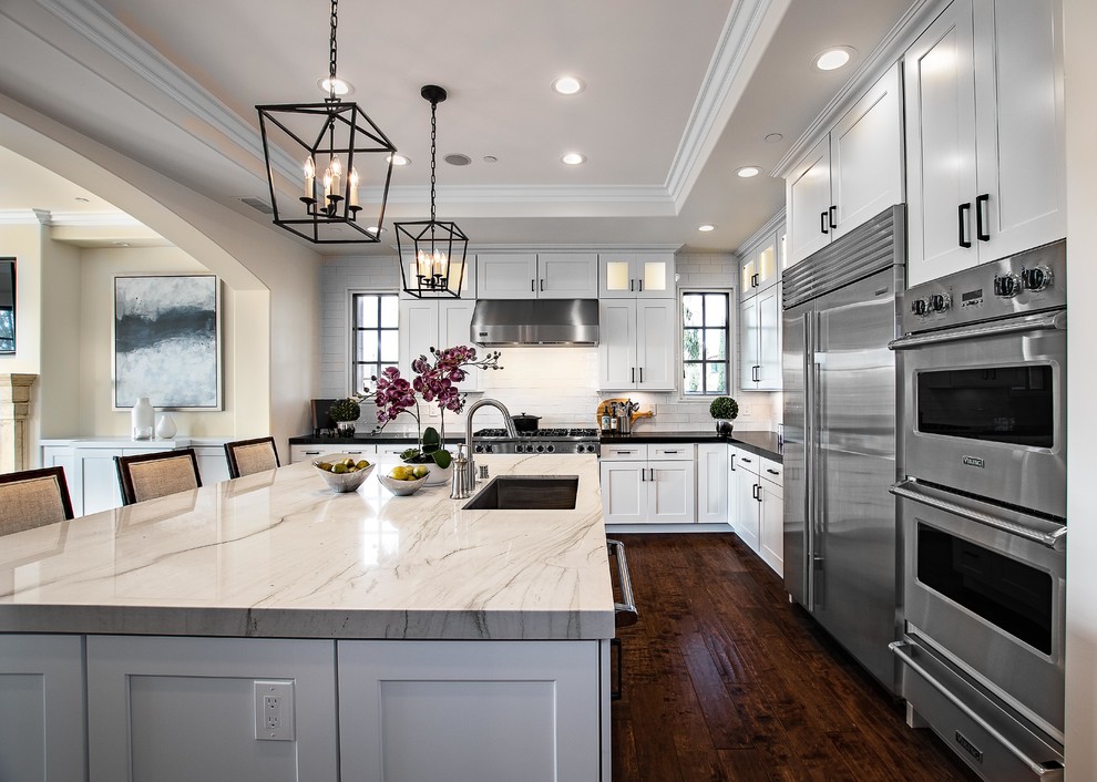 Eat-in kitchen - large transitional l-shaped dark wood floor and brown floor eat-in kitchen idea in Orange County with an undermount sink, shaker cabinets, white cabinets, quartzite countertops, white backsplash, subway tile backsplash, stainless steel appliances, an island and white countertops