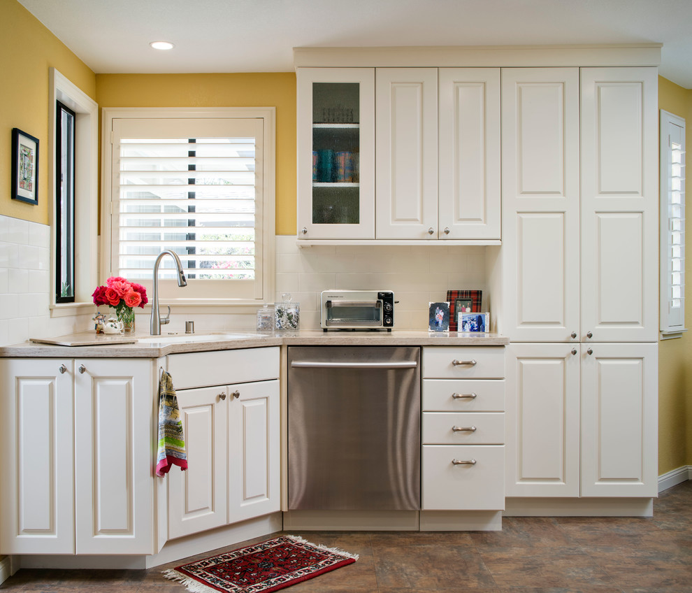 Transitional kitchen in Sacramento with an integrated sink, raised-panel cabinets, white cabinets, solid surface benchtops, yellow splashback, subway tile splashback and stainless steel appliances.