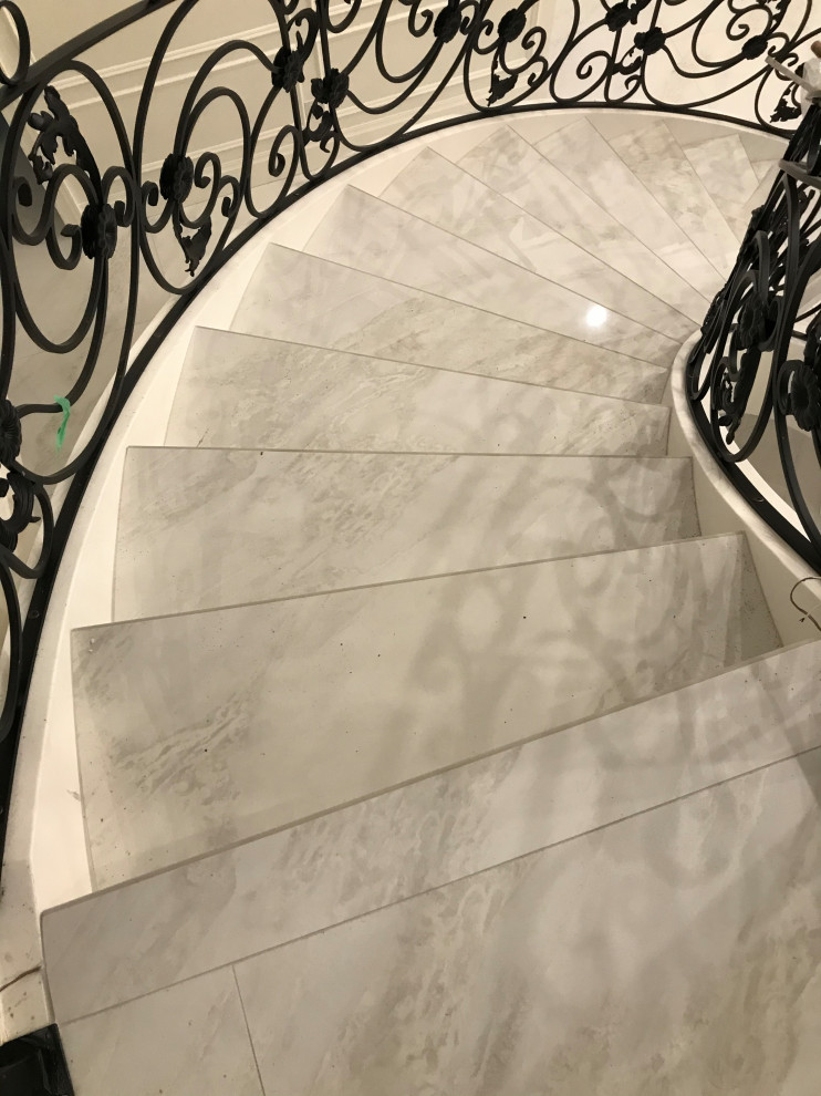 Immagine di un'ampia scala curva vittoriana con parapetto in metallo, pedata in marmo, alzata in marmo e boiserie