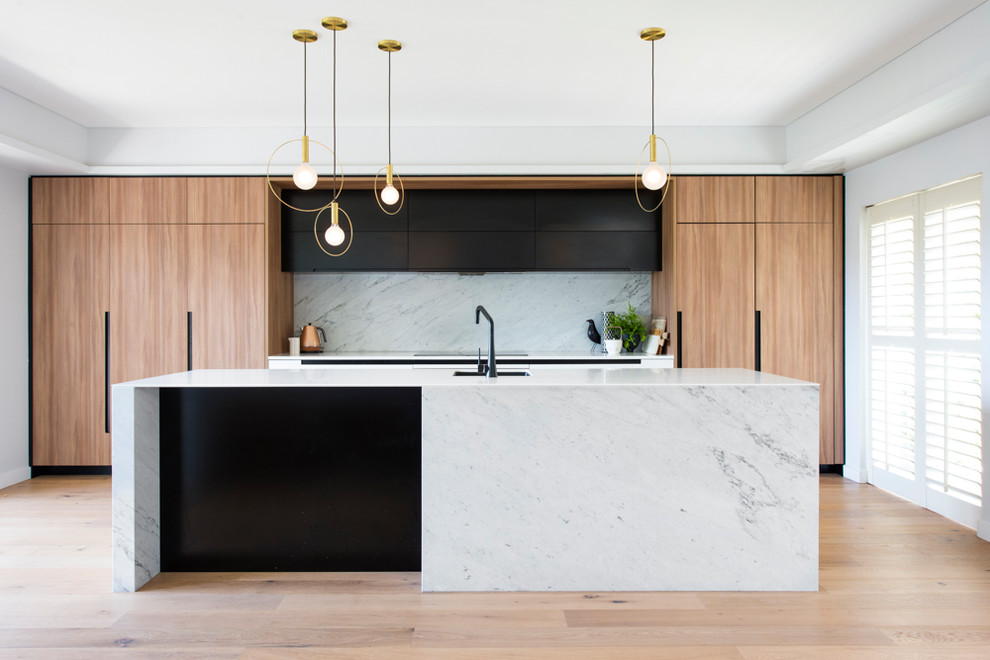 Design ideas for a mid-sized contemporary galley kitchen pantry in Sydney with an undermount sink, light wood cabinets, solid surface benchtops, white splashback, marble splashback, stainless steel appliances, light hardwood floors and with island.