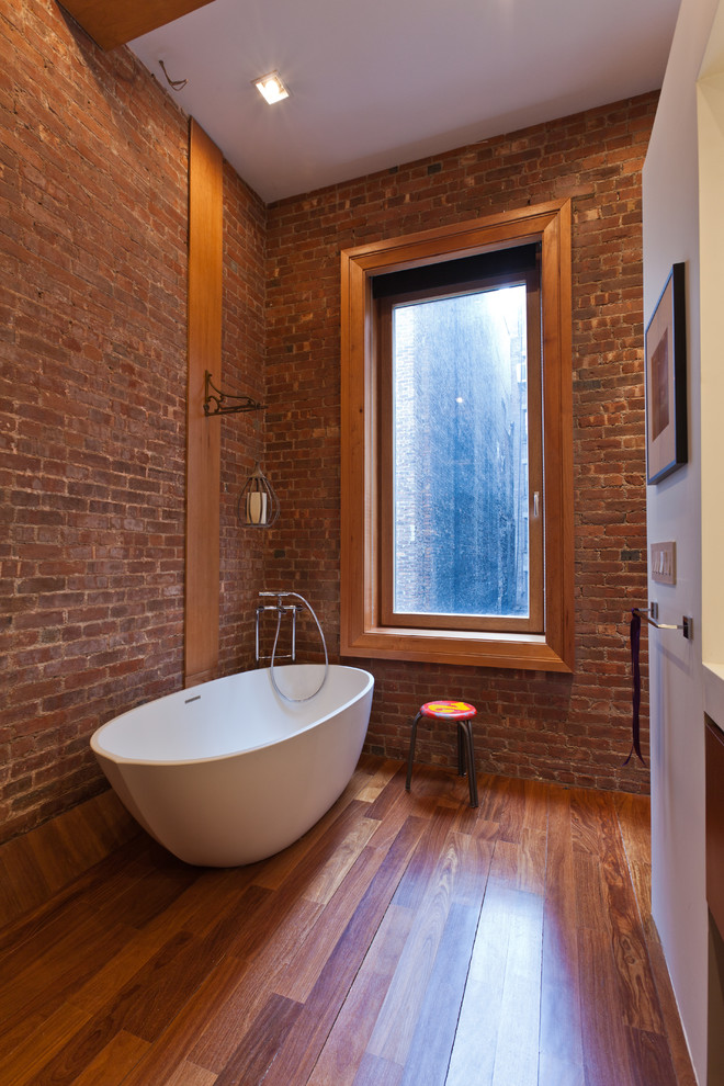 This is an example of an industrial bathroom in New York with a freestanding tub.