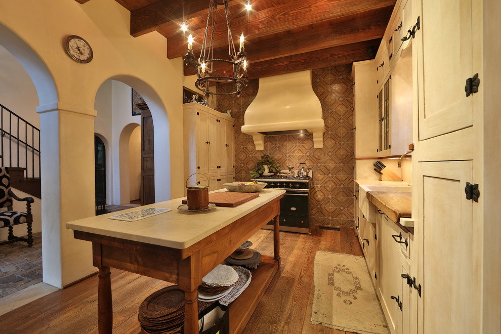 Inspiration for a mid-sized rustic single-wall medium tone wood floor and brown floor open concept kitchen remodel in Austin with a farmhouse sink, shaker cabinets, white cabinets, an island, limestone countertops, multicolored backsplash and ceramic backsplash