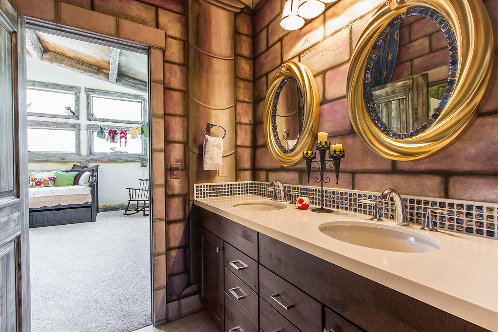 This is an example of a mid-sized transitional kids bathroom in Salt Lake City with flat-panel cabinets, dark wood cabinets, an undermount sink, a drop-in tub, a shower/bathtub combo, a one-piece toilet, multi-coloured tile, glass tile, multi-coloured walls, ceramic floors and solid surface benchtops.