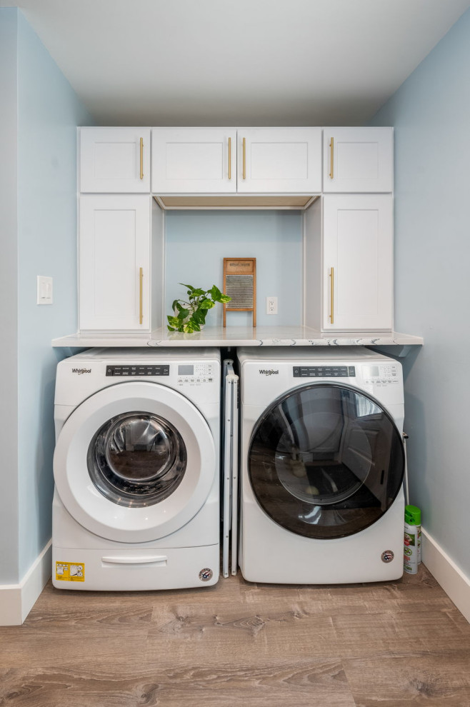 This is an example of a small single-wall dedicated laundry room in Philadelphia with a farmhouse sink, recessed-panel cabinets, white cabinets, quartz benchtops, blue walls, a side-by-side washer and dryer and multi-coloured benchtop.