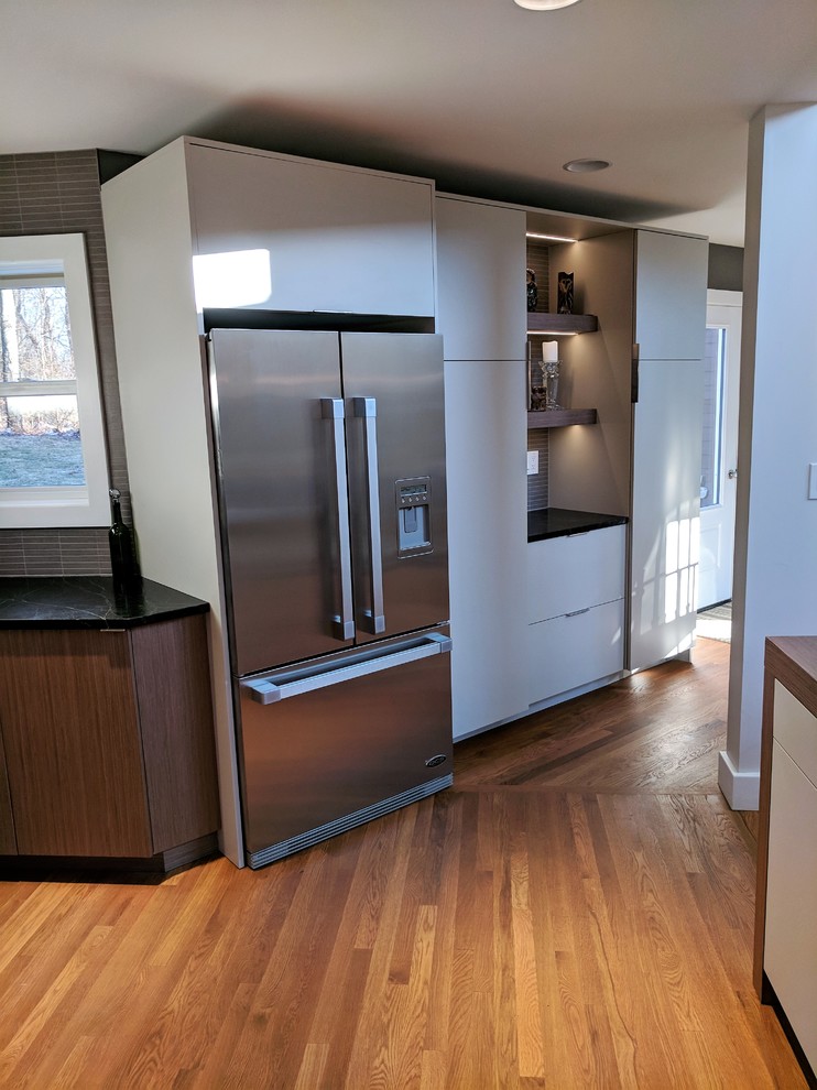 Photo of a mid-sized midcentury l-shaped eat-in kitchen in Other with an undermount sink, flat-panel cabinets, medium wood cabinets, grey splashback, porcelain splashback, stainless steel appliances, light hardwood floors and with island.