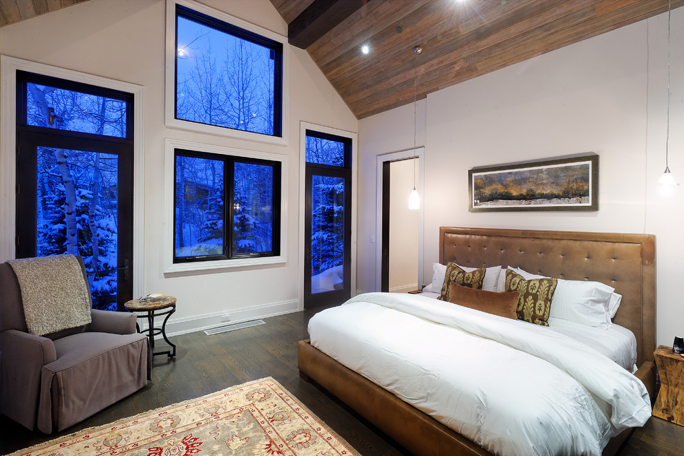 Country master bedroom in Denver with white walls and dark hardwood floors.