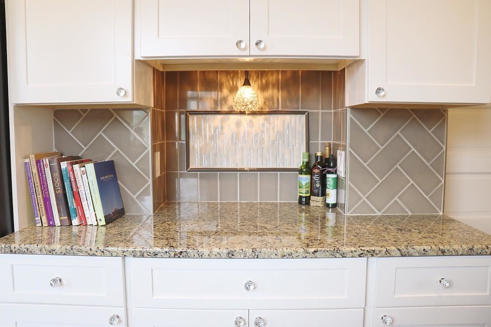 This is an example of a small traditional galley eat-in kitchen in New York with an undermount sink, shaker cabinets, white cabinets, granite benchtops, grey splashback, glass tile splashback, medium hardwood floors, a peninsula, stainless steel appliances, grey floor and beige benchtop.
