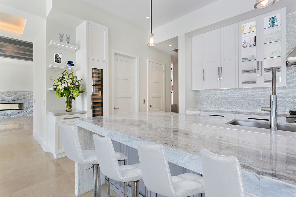 This is an example of a mid-sized transitional l-shaped open plan kitchen in Miami with an undermount sink, recessed-panel cabinets, white cabinets, marble benchtops, multi-coloured splashback, mosaic tile splashback, stainless steel appliances, ceramic floors, with island, beige floor and multi-coloured benchtop.