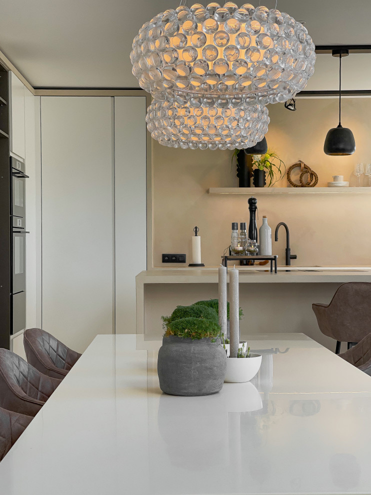 This is an example of a large modern galley kitchen/diner in Dusseldorf with a double-bowl sink, concrete worktops, black appliances, concrete flooring, an island, beige floors and beige worktops.