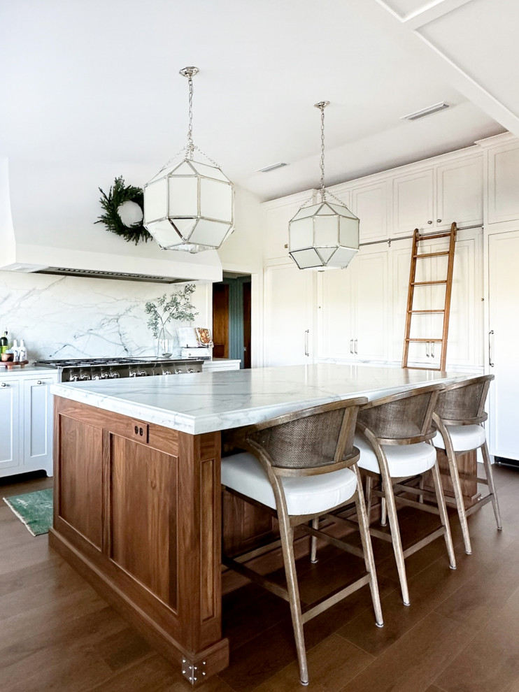 Example of a large transitional u-shaped medium tone wood floor and brown floor eat-in kitchen design with a drop-in sink, shaker cabinets, white cabinets, marble countertops, white backsplash, marble backsplash, stainless steel appliances, an island and white countertops