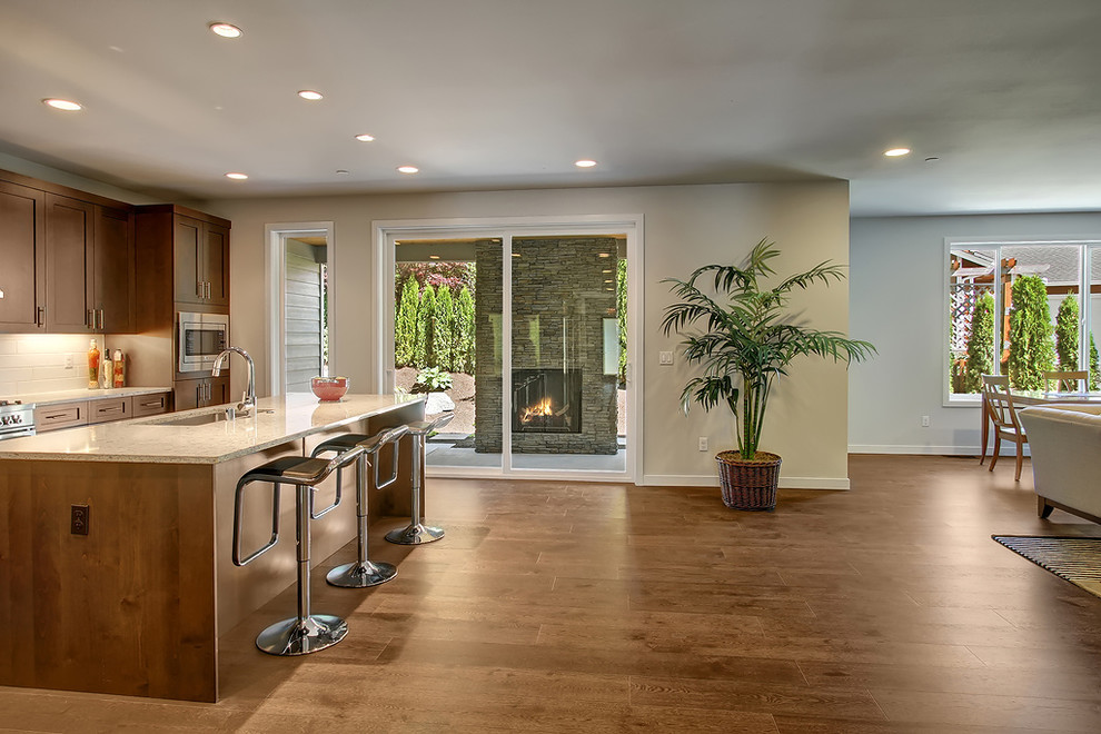 Large transitional l-shaped dark wood floor open concept kitchen photo in Seattle with a drop-in sink, shaker cabinets, dark wood cabinets, quartz countertops, white backsplash, ceramic backsplash, stainless steel appliances and an island