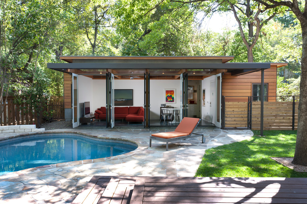 This is an example of a contemporary custom-shaped pool in Austin with a pool house.
