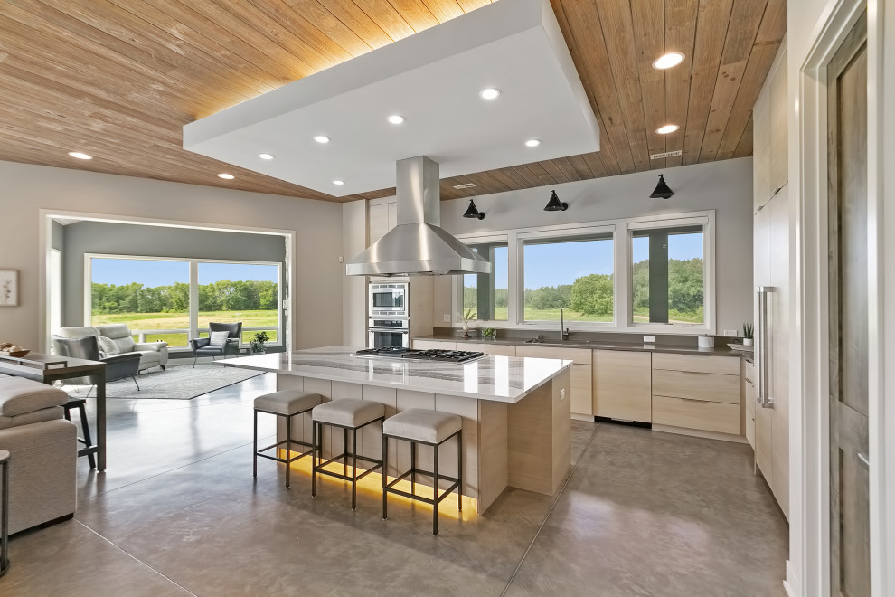 Photo of a country l-shaped kitchen in Minneapolis with an undermount sink, flat-panel cabinets, beige cabinets, quartz benchtops, panelled appliances, concrete floors, with island, beige floor, beige benchtop and wood.
