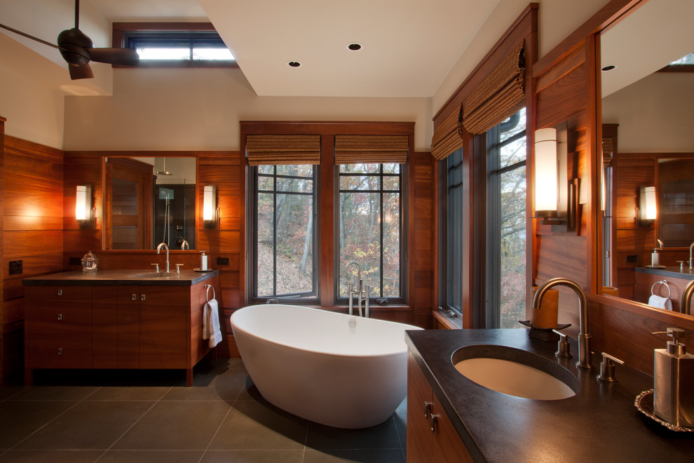Inspiration for an arts and crafts bathroom in Other with medium wood cabinets, a freestanding tub, beige walls, an undermount sink, grey floor, black benchtops and flat-panel cabinets.