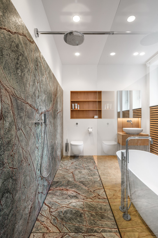 Inspiration for a contemporary master wet room bathroom in Cologne with medium wood cabinets, a freestanding tub, green tile, stone slab, white walls, medium hardwood floors, flat-panel cabinets, a wall-mount toilet, a vessel sink, wood benchtops, beige floor, an open shower and brown benchtops.