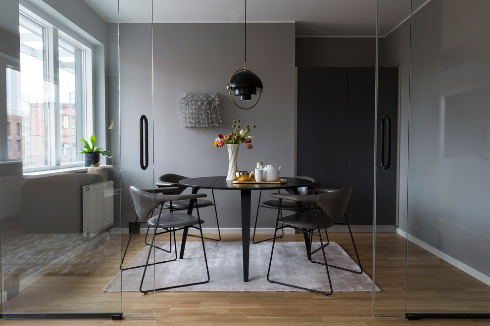 Photo of a contemporary separate dining room in Copenhagen with grey walls, light hardwood floors and beige floor.
