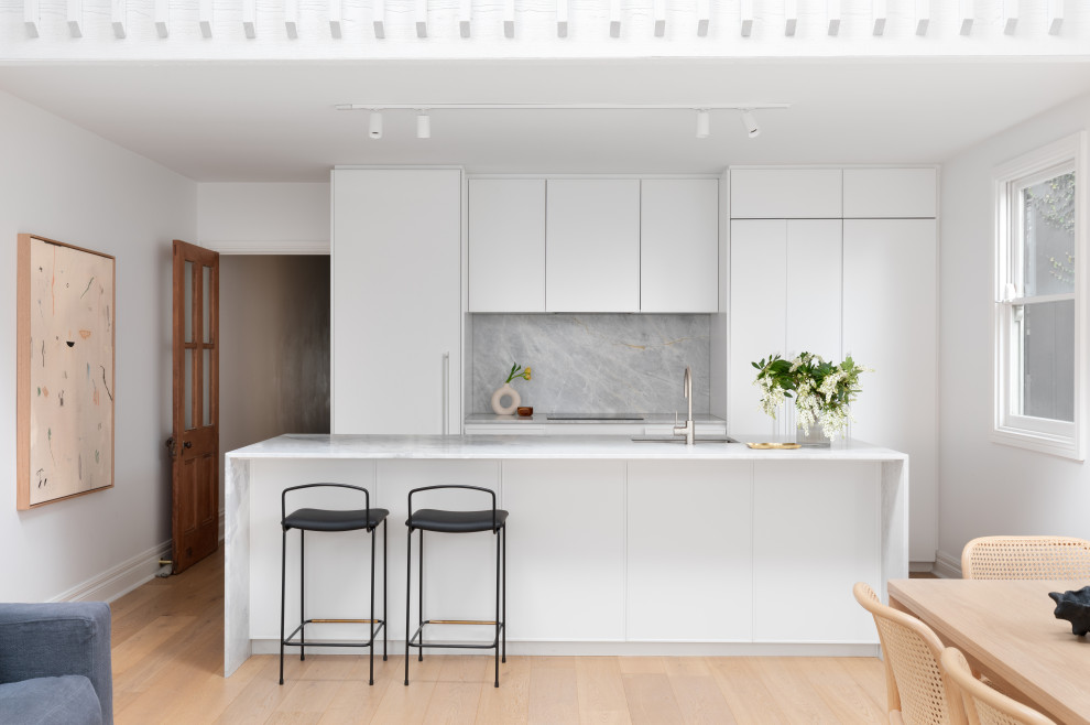 Bild på ett funkis kök, med skåp i shakerstil, vita skåp, marmorbänkskiva, stänkskydd i sten och en köksö