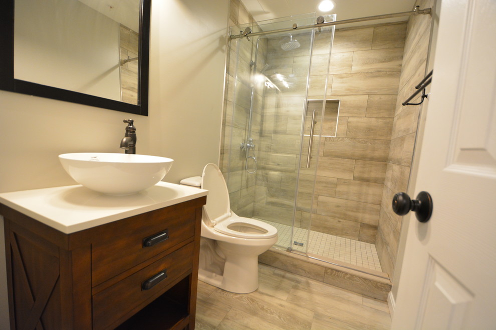 Design ideas for a mid-sized contemporary 3/4 bathroom in Baltimore with furniture-like cabinets, dark wood cabinets, an alcove shower, a one-piece toilet, beige walls, vinyl floors, a vessel sink, engineered quartz benchtops, brown floor, a sliding shower screen and white benchtops.