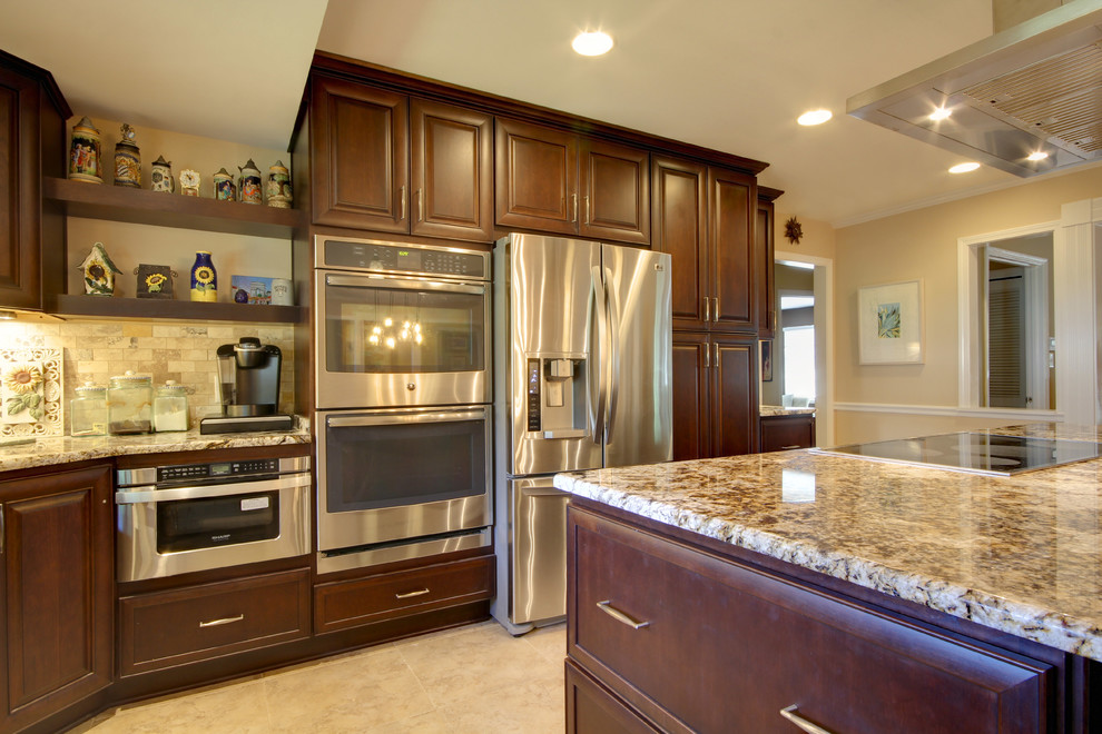 Example of a large transitional l-shaped porcelain tile eat-in kitchen design in Miami with an undermount sink, raised-panel cabinets, dark wood cabinets, granite countertops, beige backsplash, stone tile backsplash, stainless steel appliances and an island