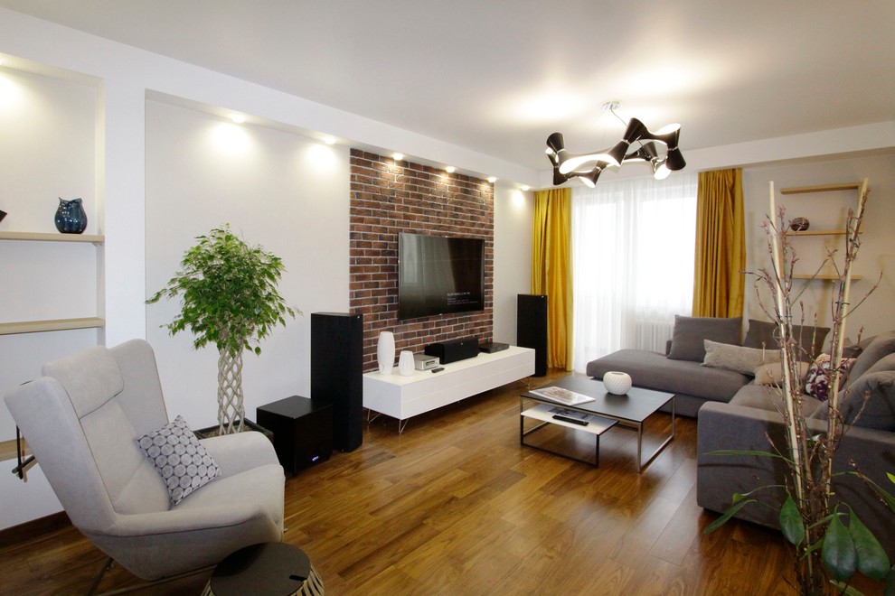 This is an example of a mid-sized industrial enclosed living room in Moscow with a library, beige walls, medium hardwood floors, a wall-mounted tv, brown floor and no fireplace.