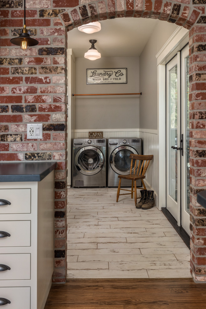 Photo of a mid-sized country dedicated laundry room in Other with grey walls, a side-by-side washer and dryer, white floor, decorative wall panelling, shaker cabinets, porcelain floors, white benchtop and white cabinets.