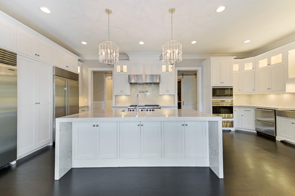 Inspiration for a large transitional l-shaped eat-in kitchen in Chicago with a farmhouse sink, shaker cabinets, white cabinets, limestone benchtops, white splashback, stone slab splashback, stainless steel appliances, dark hardwood floors, with island and brown floor.