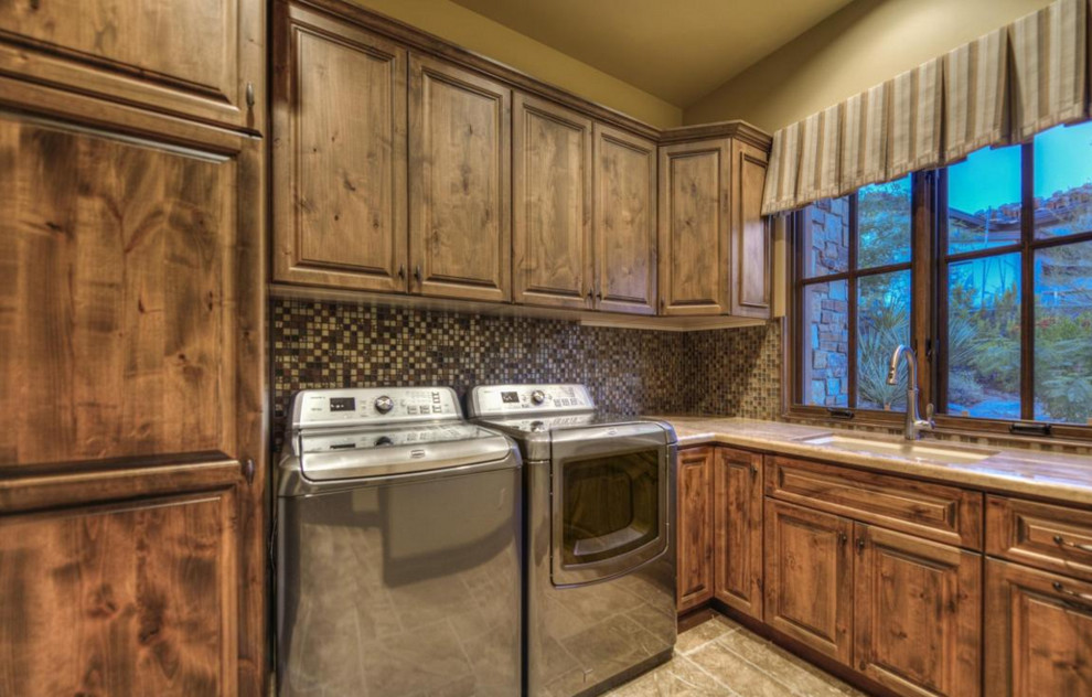 This is an example of an expansive transitional u-shaped dedicated laundry room in Phoenix with an integrated sink, flat-panel cabinets, medium wood cabinets, granite benchtops, beige walls, porcelain floors and a side-by-side washer and dryer.