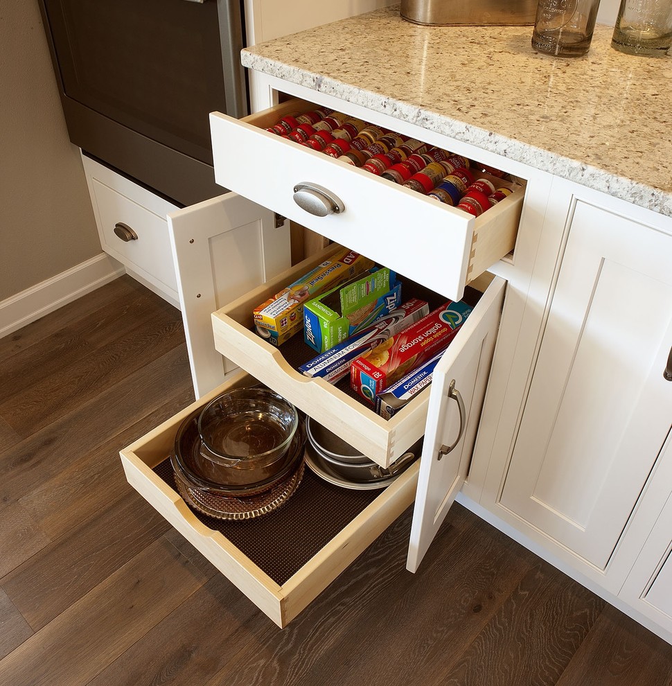 Example of a l-shaped kitchen design with stainless steel appliances and an island