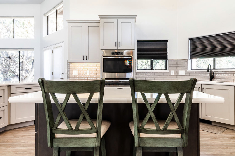 Large transitional u-shaped vinyl floor and gray floor eat-in kitchen photo with an undermount sink, shaker cabinets, gray cabinets, quartzite countertops, green backsplash, subway tile backsplash, stainless steel appliances, an island and white countertops